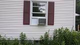 Window air conditioner unit on a house exterior with greenery around using Easy AC Screen