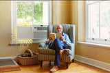 Man reading a book in a cozy living room with a window air conditioner using Easy AC Screen