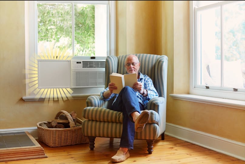 Man reading a book in a cozy living room with a window air conditioner using Easy AC Screen